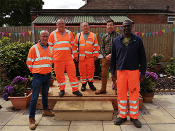 Three men standing next to each other in a garden