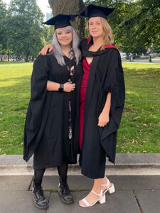 Two women dressed in graduation gowns standing next to each other