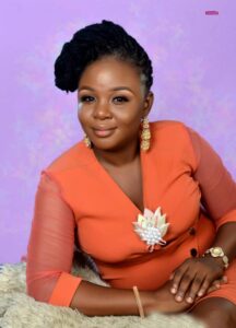 A picture of Olufunke Samuel, the subject of this article, posing for a photograph wearing an orange dress with a purple background.