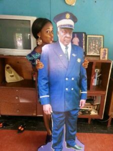 Uchenna posing with a cardboard cutout of her grandfather in uniform
